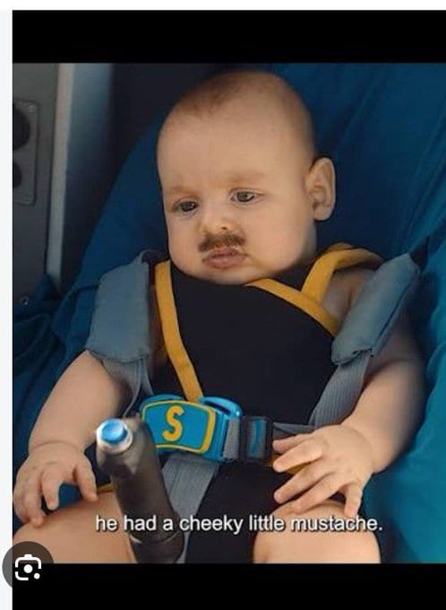 Edit of a baby with a mustache strapped into a car seat